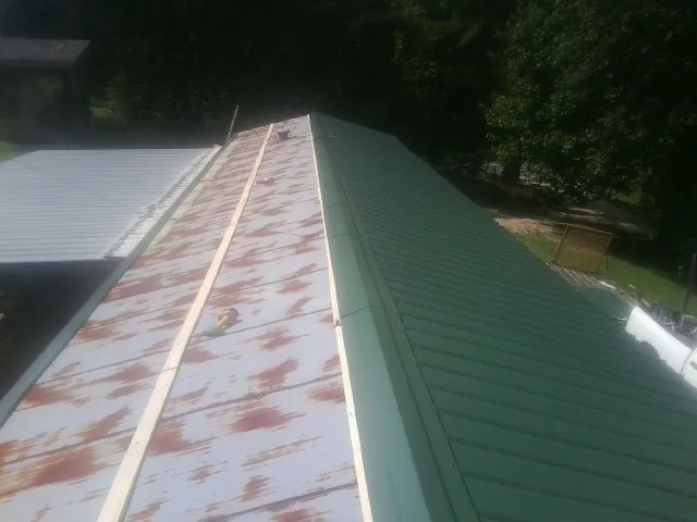 Old rusted panels beside newly installed green metal roofing — Wind Damage Roof Repair by Roofing Brothers in Plantsville