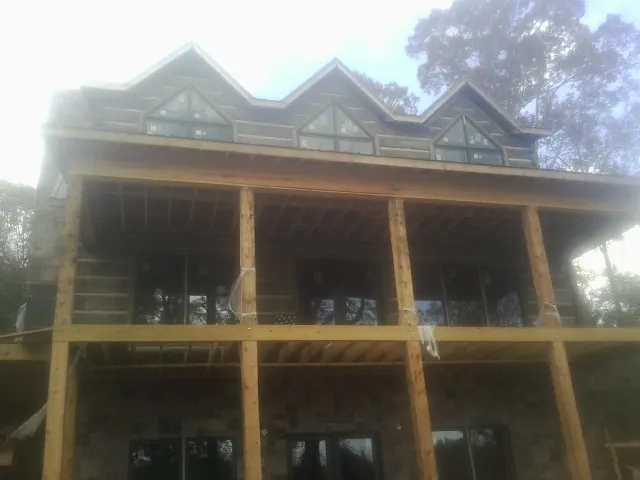 Dormers and porch framing on a large log home under construction — Roof Coating work by our crew in Plantsville