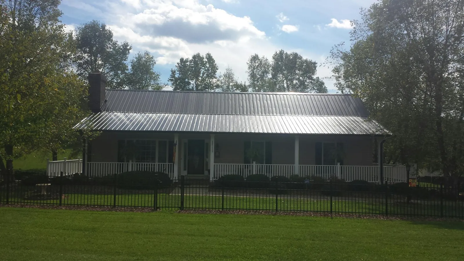 Gray metal roof on a brick ranch with a full width front porch — Gutter Guard Installation work by our crew in Plantsville