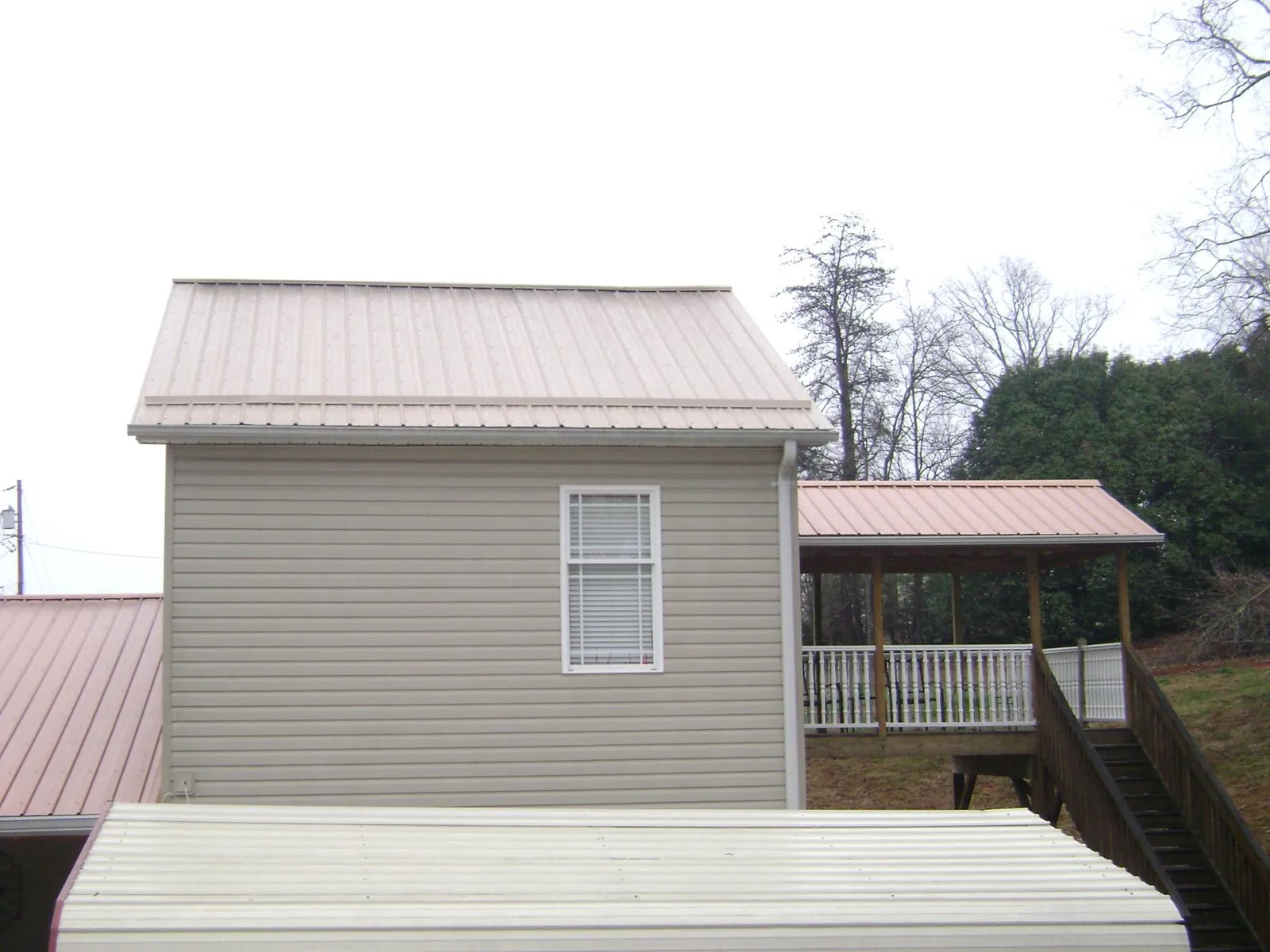Tan metal roofs on a two story addition and attached porch, from a Roof Replacement job in Plantsville
