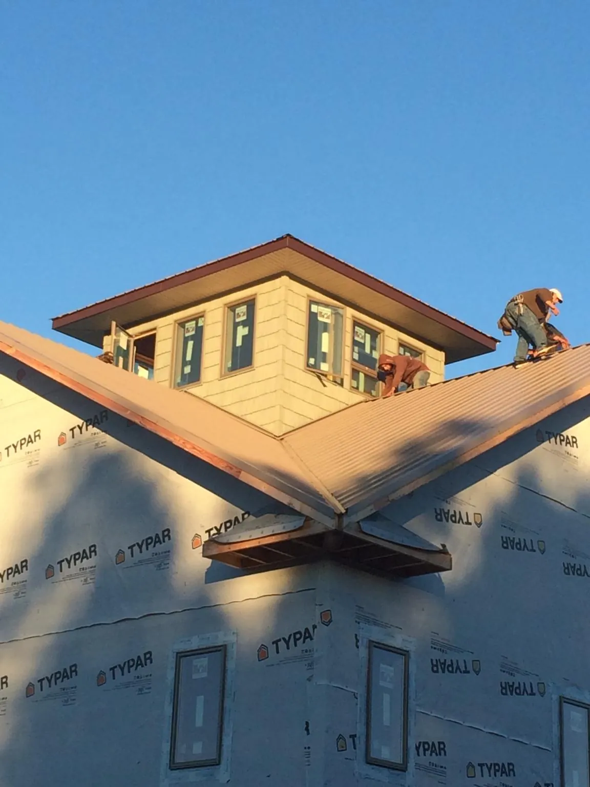 Roofers working around a rooftop cupola on a new metal roof at sunset — Roof Waterproofing in Plantsville by Roofing Brothers
